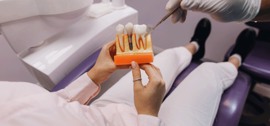 Patient in chair holding a dental implant model with thew doctor giving information
